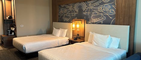 Habitación de hotel con dos camas, una mesita de noche, una lámpara de pared y un panel decorativo.