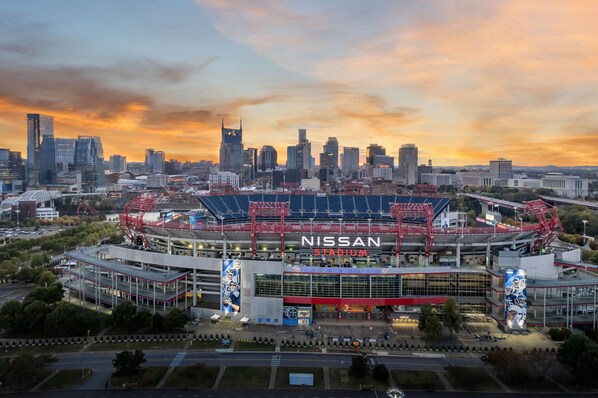 A stadium with a large "NISSAN" sign, surrounded by a cityscape at sunset. - La Quinta Inn & Suites by Wyndham Nashville Downtown / Stadium (Nashville)