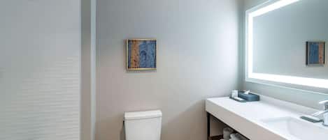 Een moderne badkamer met toilet, wastafel met spiegel en douche.