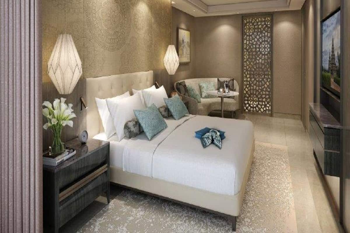Une chambre moderne avec un grand lit, des tables de chevet, un coin salon et un mur décoratif.