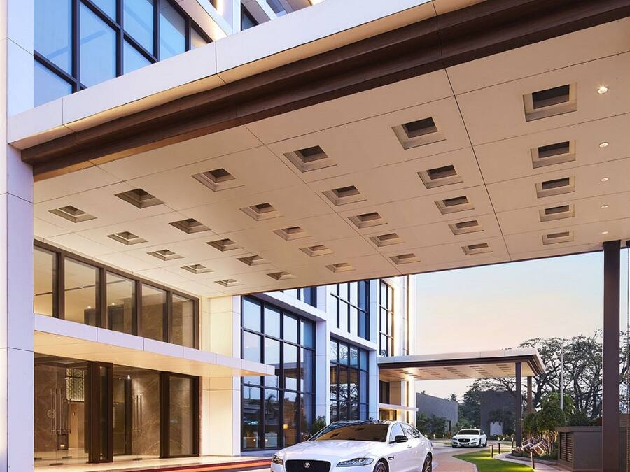 A modern building with a covered entrance, large windows, and a car parked in front.