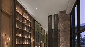 Een ruime lobby met een grote zithoek, een wand met decoratieve vazen en uitzicht door grote ramen.
