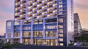 Een hotel met meerdere verdiepingen, in modern design, met balkons bij elk verdiep en grote ramen.