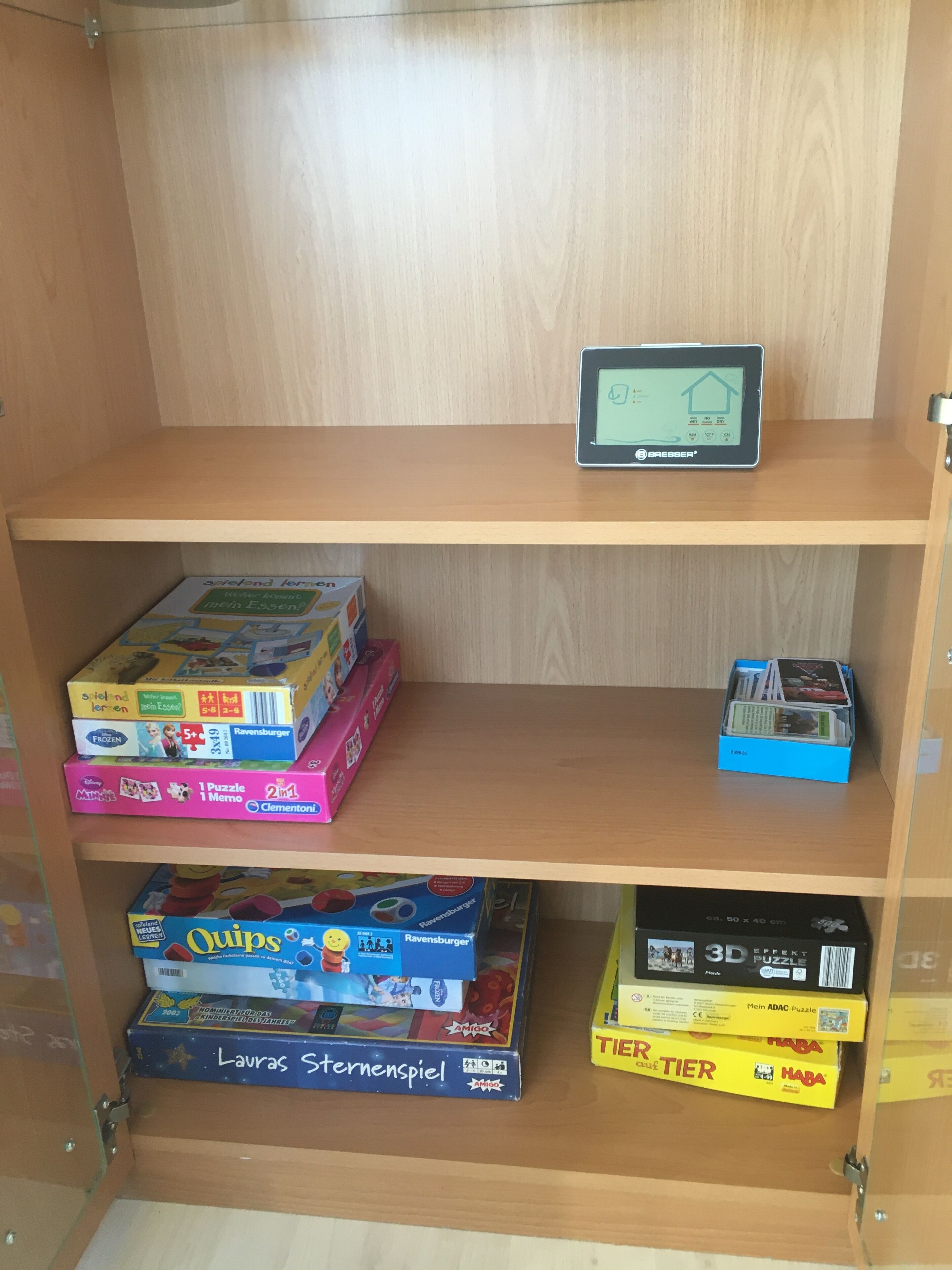 A wooden shelf with various board games and a Besser tablet.
