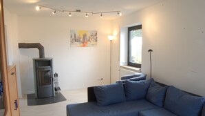 A modern living room with a gray sofa, a small table, a fireplace, and a painting on the wall. - Wohnung mit Kamin Terrasse und Grill in der Nähe von Nürnberg (Burgthann)