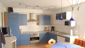 A modern kitchen with blue cabinets, a built-in oven, and a microwave. - Wohnung mit Kamin Terrasse und Grill in der Nähe von Nürnberg (Burgthann)