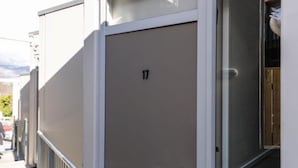 A building with a numbered door, a window, and a metal railing. - Mountain View City Aparment (Queenstown)