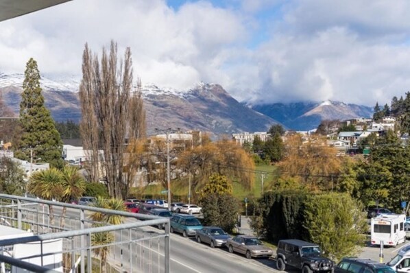 A view of a road with vehicles, a mountain range, and buildings in the background.