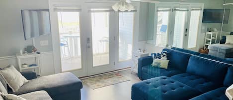 A spacious living room with a blue sofa set, a white chair, and a ceiling fan.