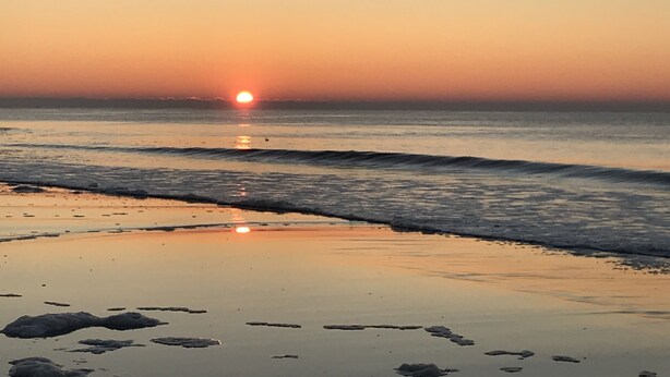 A beach scene with the sun setting over the ocean. - Family Time Oceanfront Condo at Ocean Isle (Ocean Isle Beach)