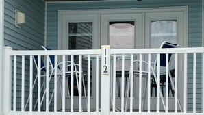 A two-story building with a balcony on the upper floor, featuring a white railing and a door with a number "12" sign. - Family Time Oceanfront Condo at Ocean Isle (Ocean Isle Beach)
