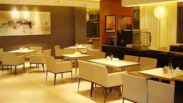A restaurant with multiple tables and chairs, a bar area, and a large abstract painting on the wall.