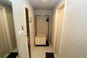 A narrow hallway with a shower stall, a door with a handle, and a small cabinet. - Jinjiang Inn (Lianyungang Xinpu Park Pedestrian Street) (Lianyungang)
