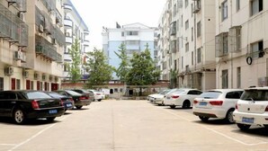 Un parking où les voitures sont rangées en rangées, entouré d’immeubles à plusieurs étages dotés de balcons et de fenêtres.