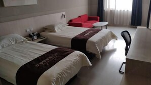Une chambre d’hôtel avec deux lits, un canapé rouge, une petite table ronde et un bureau.
