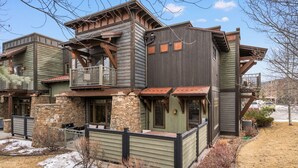 Un immeuble à plusieurs étages, doté de fondations en pierre, de balcons en bois et d’une clôture en métal.