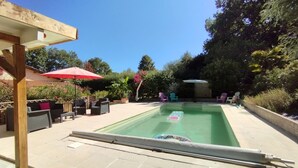 Una piscina rectangular con superficie de agua azul cristalina, rodeada por una zona de patio con baldosas.