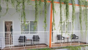 Un balcon avec une balustrade blanche, des chaises noires et une table.