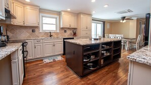 A modern kitchen with white cabinetry, a granite countertop island, and a wooden floor. - La Bella Vita: Spectacular Cayuga Lake Sunsets! (Cayuga)