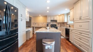 A modern kitchen with white cabinetry, a central island, and a stainless steel refrigerator. - La Bella Vita: Spectacular Cayuga Lake Sunsets! (Cayuga)
