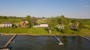A lakeside property with multiple houses, a dock, and a grassy area. - La Bella Vita: Spectacular Cayuga Lake Sunsets! (Cayuga)
