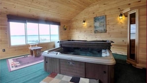 A wooden cabin interior with a hot tub, a window with a view, and a painting on the wall. - La Bella Vita: Spectacular Cayuga Lake Sunsets! (Cayuga)