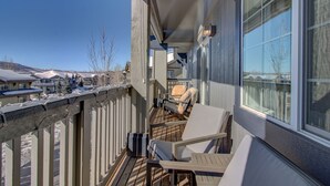 En balkong med utemöbler, utsikt över ett snötäckt landskap och en klar himmel.