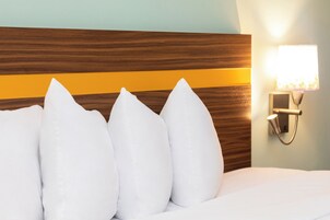 A bed with white pillows and a wooden headboard with a horizontal stripe.