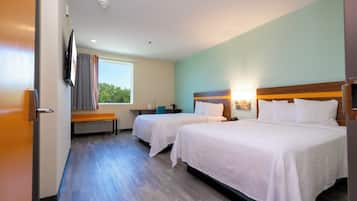 Quarto de hotel com duas camas, uma escrivaninha, uma cadeira, janela com cortinas e TV de tela plana na parede.