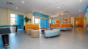 A modern hotel lobby with a pool table, comfortable seating, and a reception area. - SPOT X Hotel Orlando/Intl Dr by The Red Collection (Orlando)