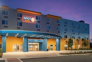 Een modern hotel met een opvallend 'SPOT HOTEL' bord, een gebogen entree en het nummer '12235' op de gevel.