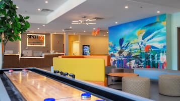 A hotel lobby with a foosball table, seating area, and a large cityscape mural.