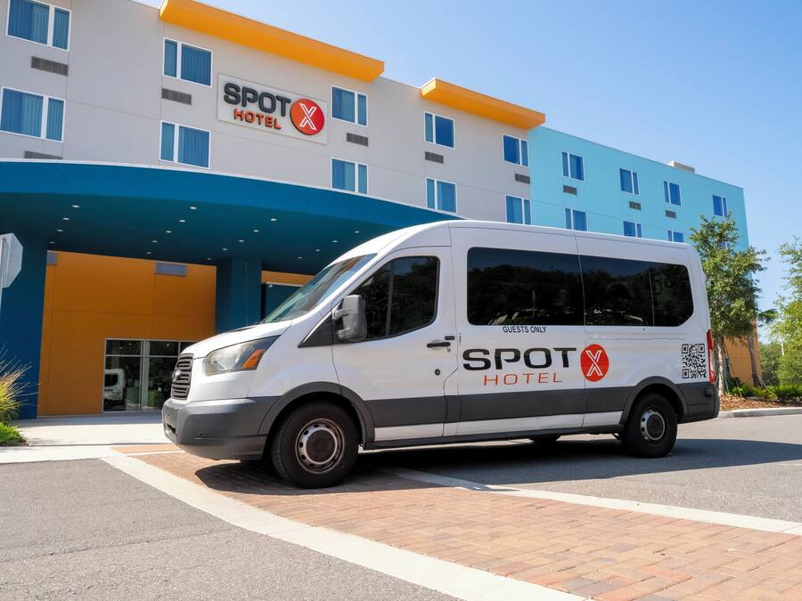 Una camioneta con la marca 'SPOT HOTEL' estacionada frente a un edificio de hotel.