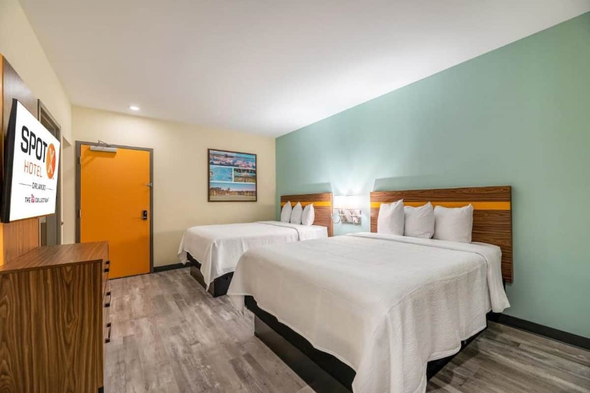 A hotel room with two beds, a wooden dresser, and a framed picture on the wall.