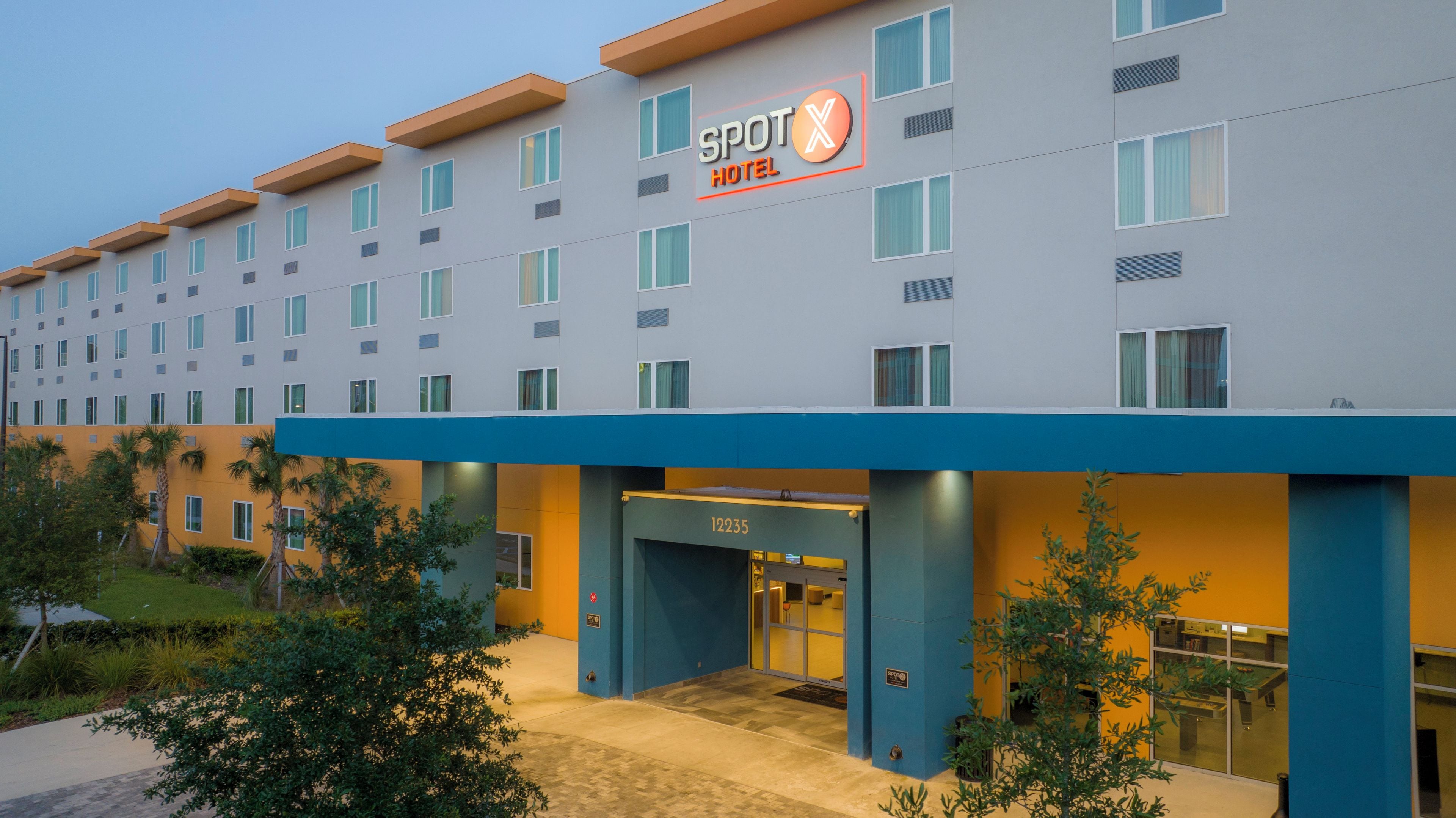 Um hotel com fachada moderna, um letreiro chamativo com a inscrição 'SPOT HOTEL' e o número '12235' na entrada.