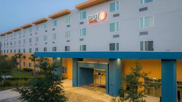 Um hotel com fachada moderna, um letreiro chamativo com a inscrição 'SPOT HOTEL' e o número '12235' na entrada.