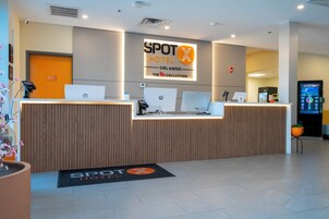 A hotel reception desk with multiple HP computers, a digital screen, and a reception area with a wooden finish.