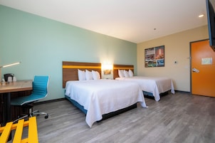 Een hotelkamer met twee bedden, een bureau met stoel en een aan de muur hangend kunstwerk.