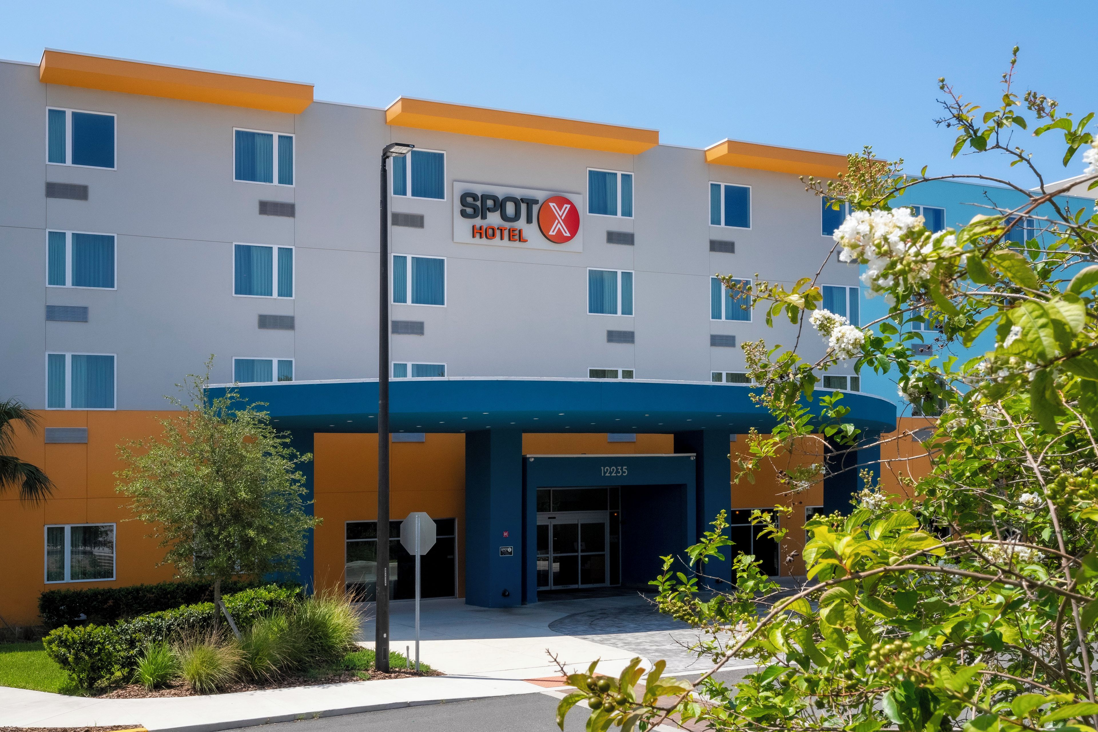 A modern hotel with a sign reading "SPOT X HOTEL" and the number "12235" on the entrance.