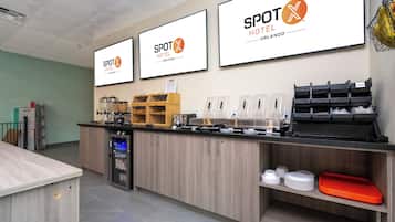 A hotel reception area with a counter, coffee machines, and a refrigerator.