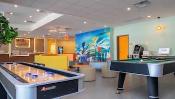 A hotel lobby with a pool table, a billiards table, and a reception desk.