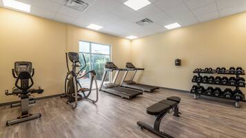 A gym with treadmills, an elliptical, a bench, and a rack of dumbbells.