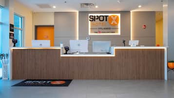 Un comptoir d’accueil d’hôtel équipé d’ordinateurs HP, d’un écran numérique et d’une enseigne indiquant « SPOT HOTEL ORLANDO ».