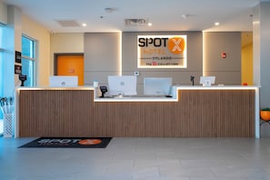 Een receptiebalie van een hotel met HP computers, een digitaal scherm en een bord met de tekst SPOT HOTEL ORLANDO.
