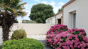 A residential area with a white building, a large tree, and a hedge of pink flowers. - Villa 12 pers : 6 bedrooms, 3 bathrooms, 3wc/ 200m from the beach of La Sauzaie (Bretignolles-sur-Mer)