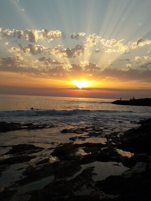 A sunset over a rocky shoreline with waves.