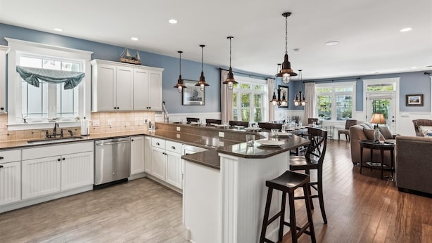 A spacious kitchen with white cabinets, a large island, and pendant lighting. - 221 Wellington Parkway (Bethany Beach)
