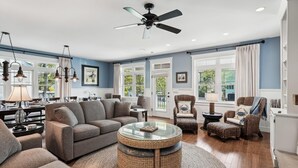 A spacious living room with a grey sofa, wicker coffee table, and wicker chairs. - 221 Wellington Parkway (Bethany Beach)