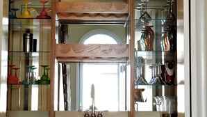 A kitchen with wooden cabinets, a glass-fronted wine rack, and a 'Happy Hour' sign. - Spacious 6BR Family Home – Just 3 Blocks to Bethany Beach in The Canal Community (Bethany Beach)