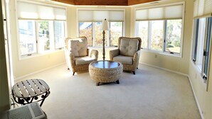 A sunlit room with two wicker armchairs, a small round table, and a metal chair. - Spacious 6BR Family Home – Just 3 Blocks to Bethany Beach in The Canal Community (Bethany Beach)